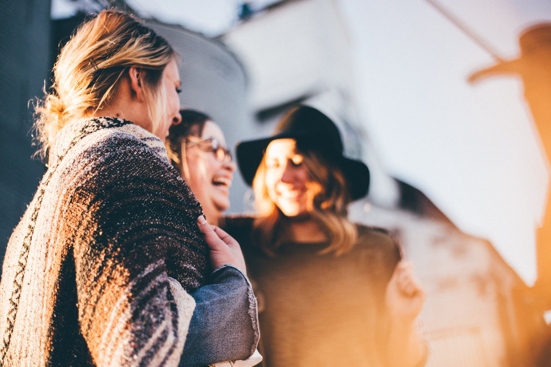Drie vrouwen praten en lachen samen buiten.